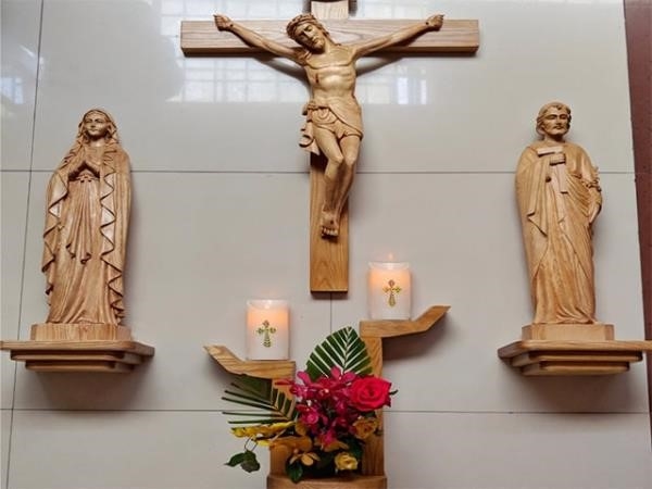 Bàn thờ Chúa trong phòng khách được thiết kế từ gỗ và được trang trí bằng hoa tươi và nến bên dưới để mang lại cảm giác tôn nghiêm cho nơi này.
